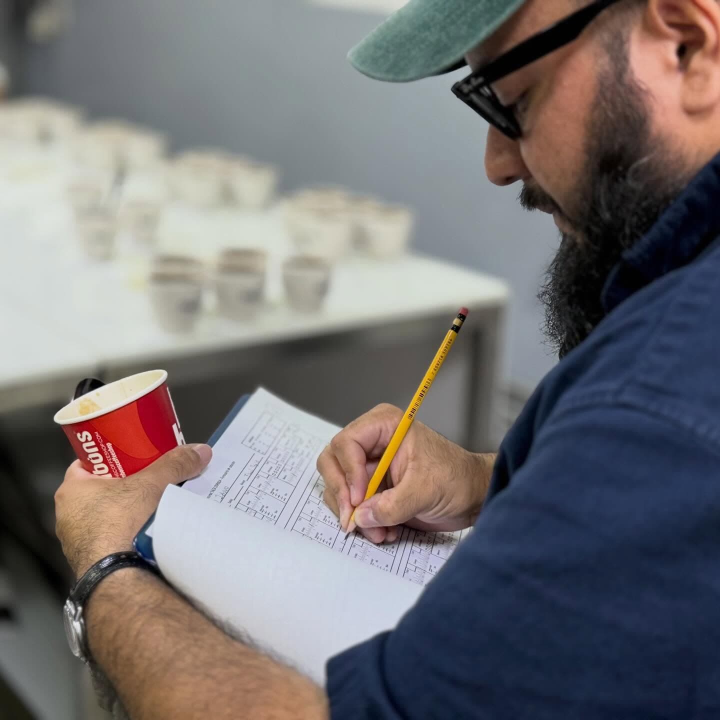 Juez anotando su calificación junto a la taza de muestra durante la evaluación